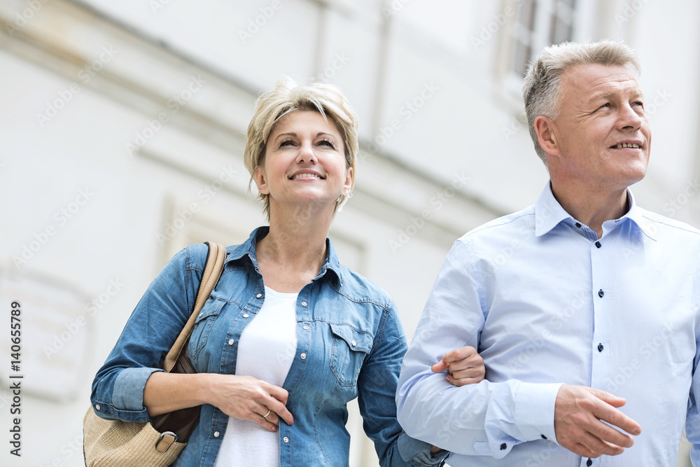 Smiling middle-aged couple standing with arm in arm outdoors Smiling middle-aged couple standing with arm in arm outdoors