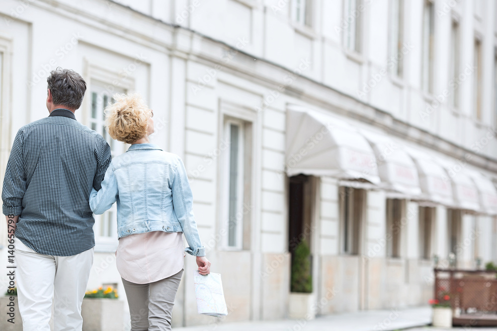Rear view of middle-aged couple walking by building Rear view of middle-aged couple walking by building