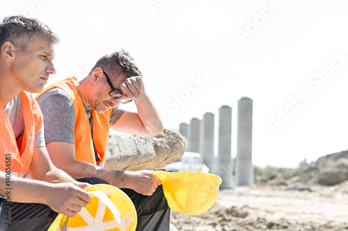 Photography Tired supervisor sitting with colleague at construction site