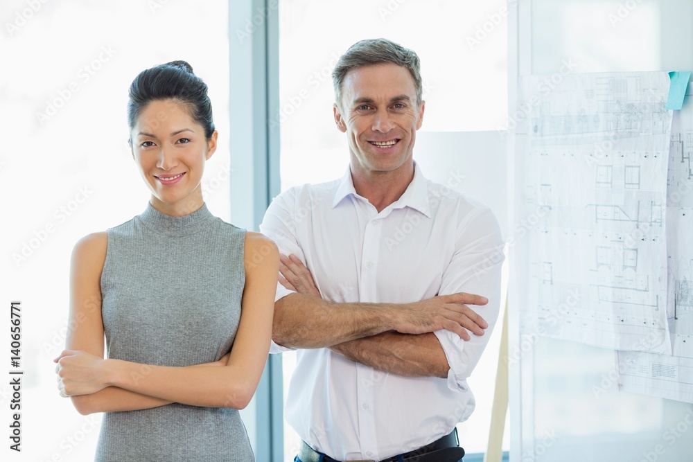 Fototapeta premium Smiling architects standing with arms crossed in office