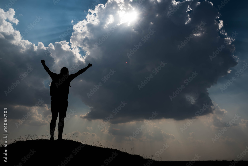 Silhouette of man with hands raised and sky with sunlight Silhouette of man with hands raised and sky with sunlight