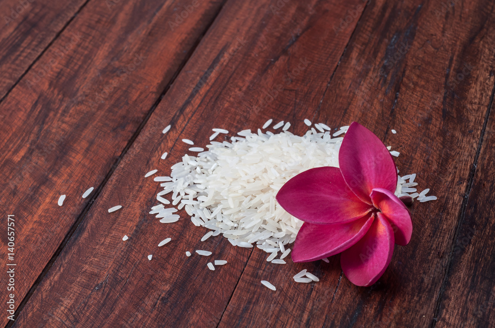 White Jasmine rice with pink plumeria flower on dark wooden table White Jasmine rice with pink plumeria flower on dark wooden table