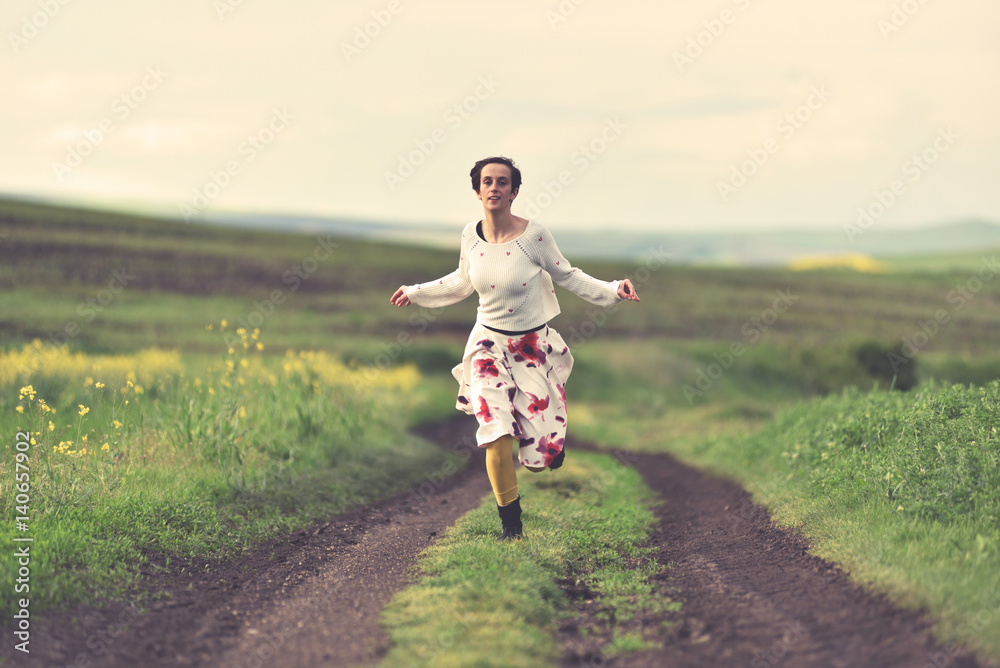 Fototapeta premium Woman in white skirt running on a countryside road