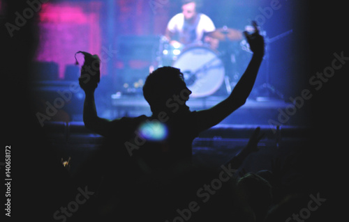 Rear view of a man with raised arms enjoying a concert