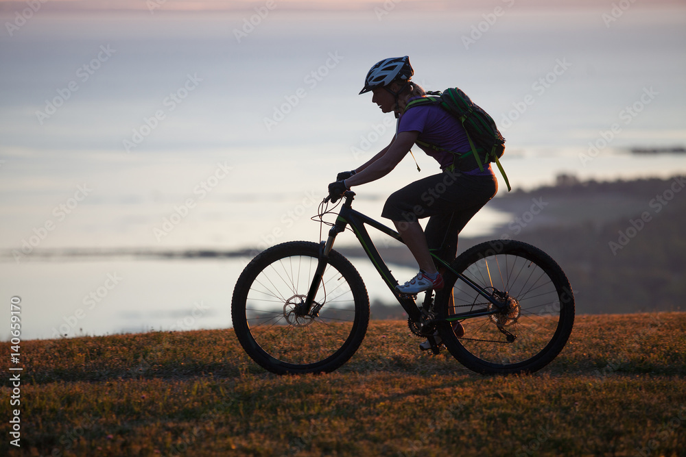 Woman mountain biking on single track trail at Sunset