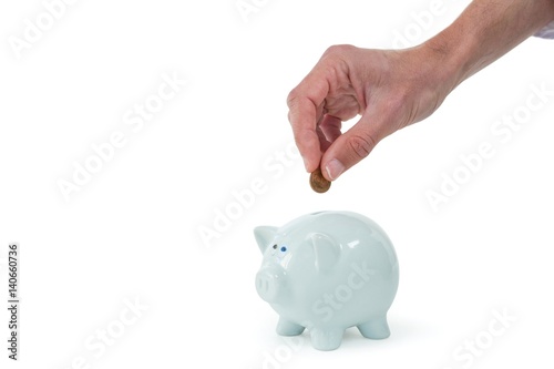 Photography Hand inserting coin in piggy bank