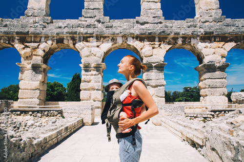 Photography Mother with baby in carrier in the old town of Pula, Croatia.