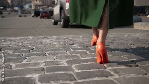 Sexy woman legs walking on cobblestone street photo