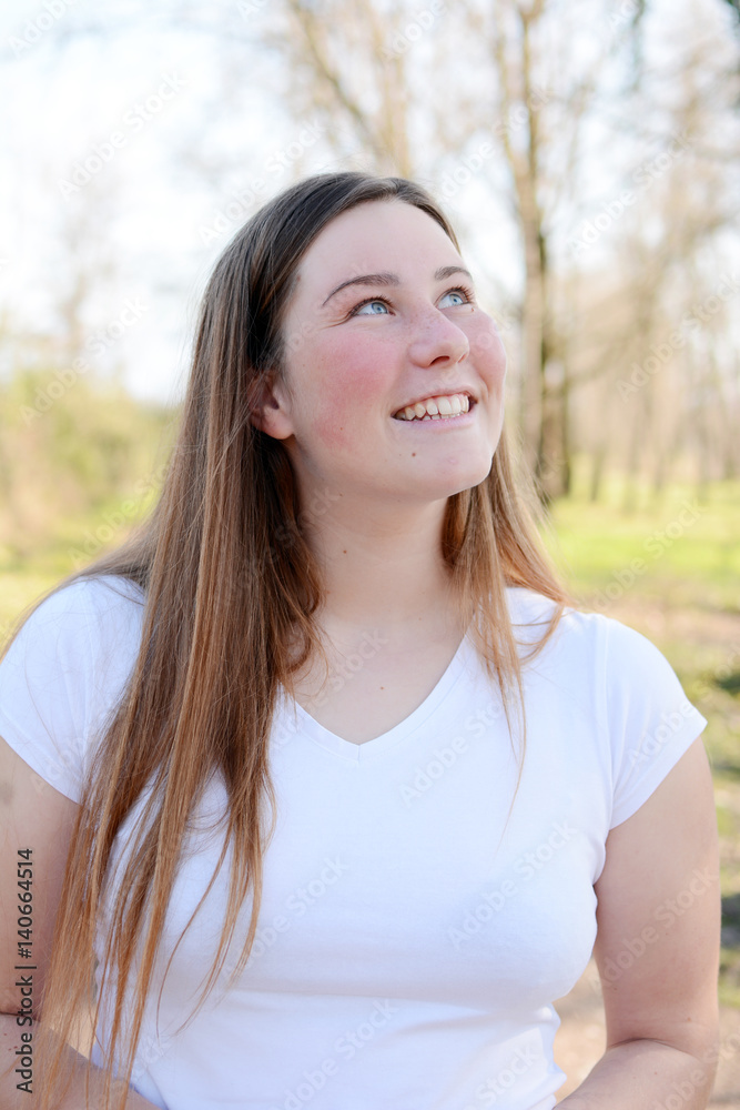 Portrait of happy beautiful young woman enjoying sun light in the park.