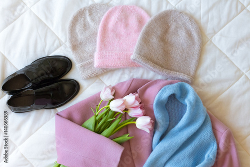 Manually knitted hats, black patent leather shoes, pink cashmere coat, blue woollen scarf and fresh pink tulips
