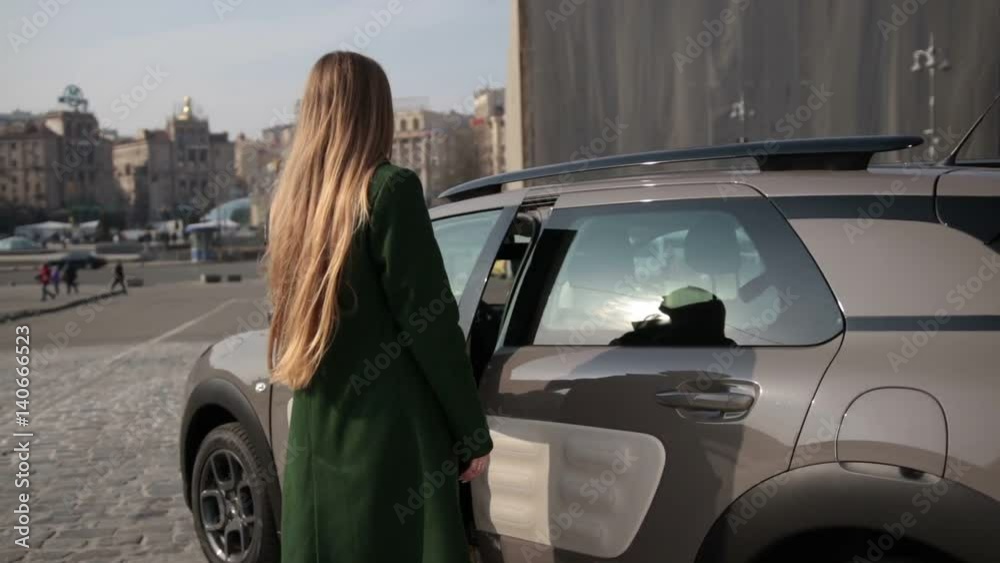 Back view of fashionable woman getting into car