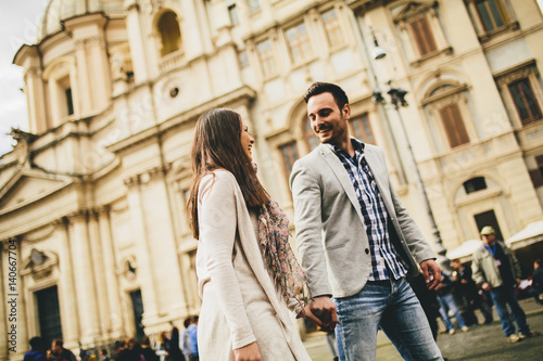 Casual young couple holding hands walking in Rome, Italy, Europe