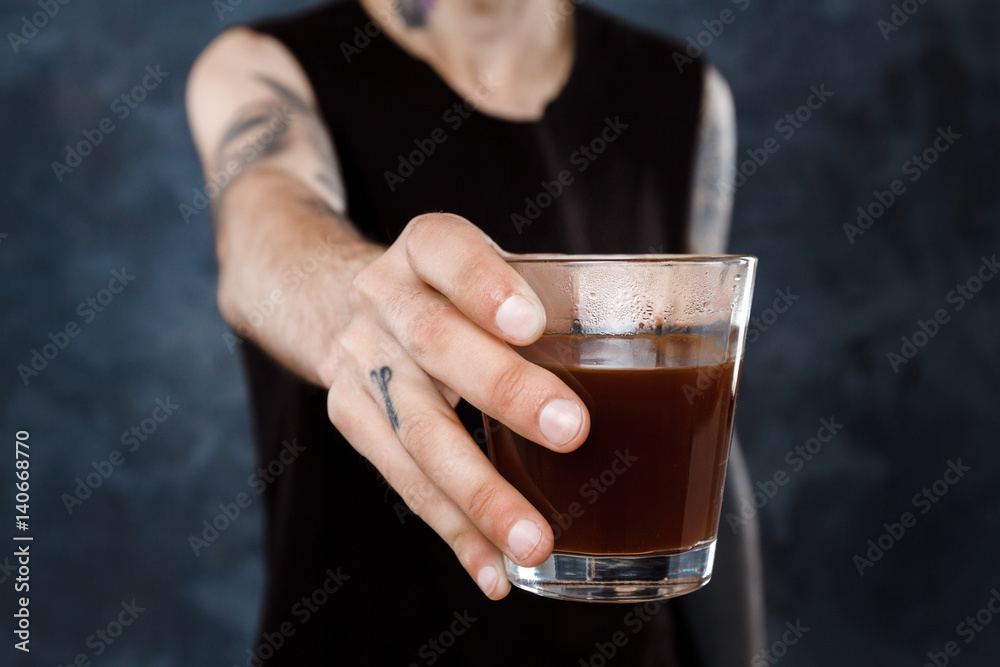 Male barista stretching glass with coffee to camera.