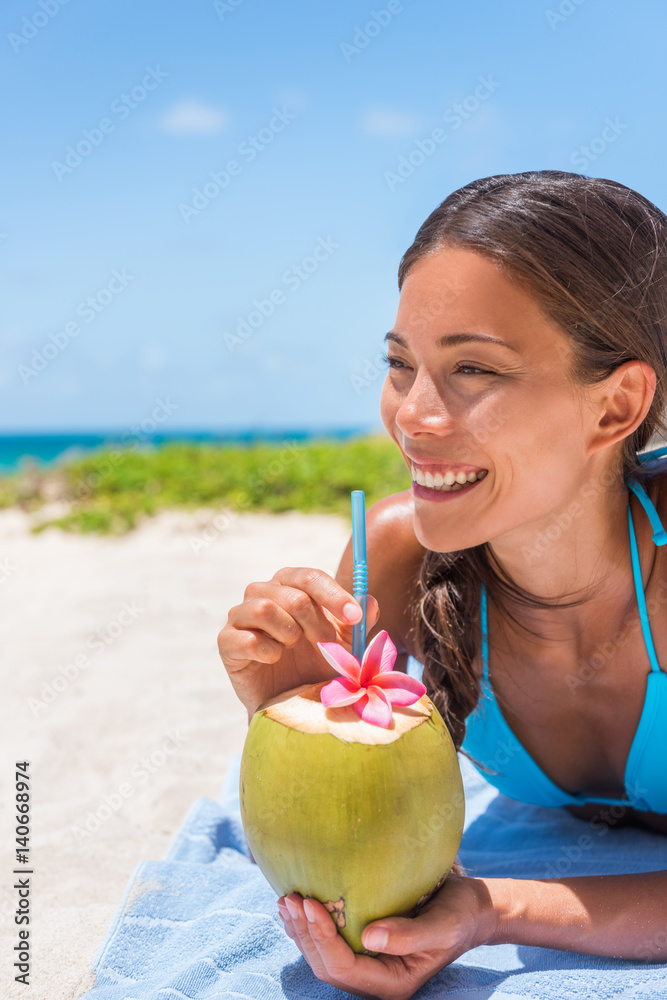 Happy Asian girl drinking fresh coconut water on beach vacation. Tropical  travel destination, Sun tanning in summer holidays. Tourist woman relaxing  enjoying drink. Stock Photo