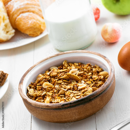 Healthy food for breakfast on a white wooden table. Oatmeal granola with nuts, coffee, croissants, eggs, milk and fruits for delicious healthy meal. © Maxim Khytra