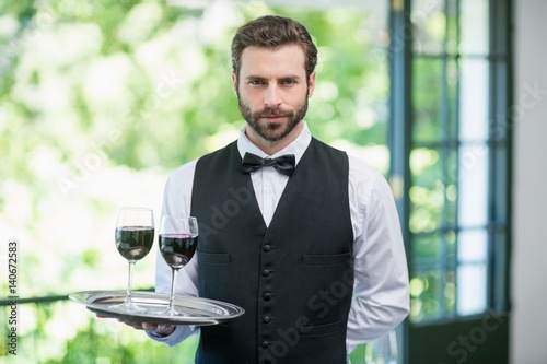 Male waiter holding tray with wine glasses