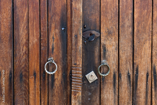 Wooden brown door of planks with metal handles and keyhole © Emil
