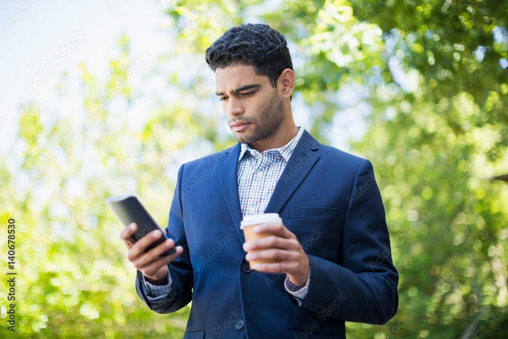 Businessman holding disposable coffee cup and using mobile phone Businessman holding disposable coffee cup and using mobile phone