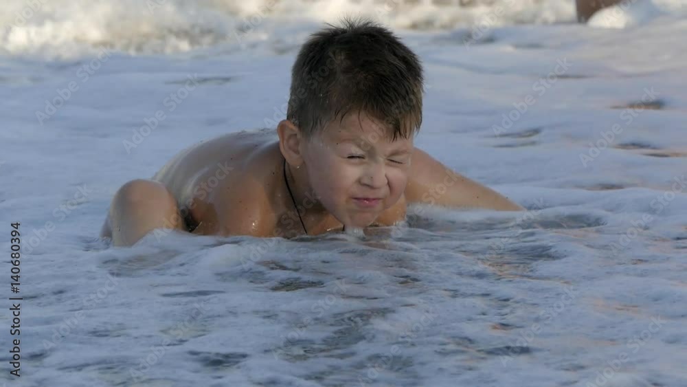 Cute little baby sitting on the beach and enjoying the waves playing with the sand. Slow motion Cute little baby sitting on the beach and enjoying the waves playing with the sand. Slow motion