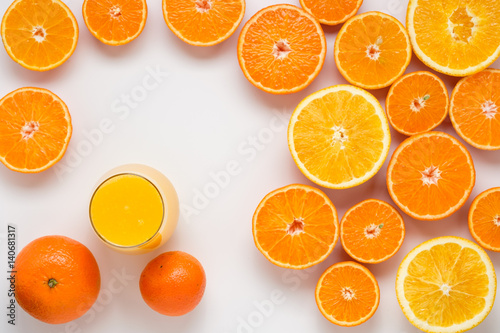 A glass of juice and cut oranges and tangerines on a white background