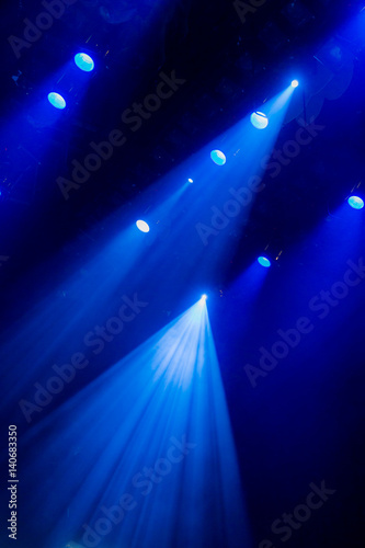 The blue light from the spotlights through the smoke in the theatre during the performance. Lighting equipment.