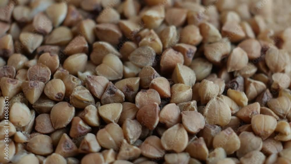 Rotating raw buckwheat. Spinning closeup dry uncooked seeds. Rotating raw buckwheat. Spinning closeup dry uncooked seeds.
