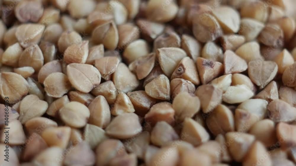 Rotating raw buckwheat. Spinning closeup dry uncooked seeds. Slow motion. Rotating raw buckwheat. Spinning closeup dry uncooked seeds. Slow motion.