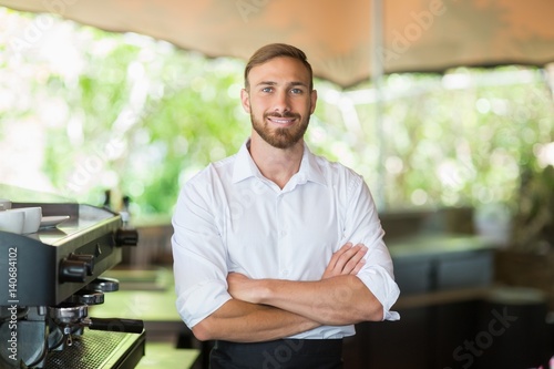Waiter standing with arms crossed at restaurant