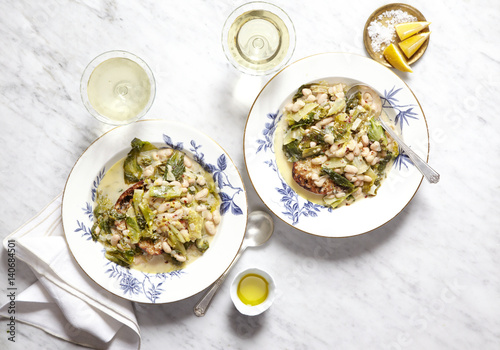 Cannellini beans and escarole stew over bread with lemon in two bowls.