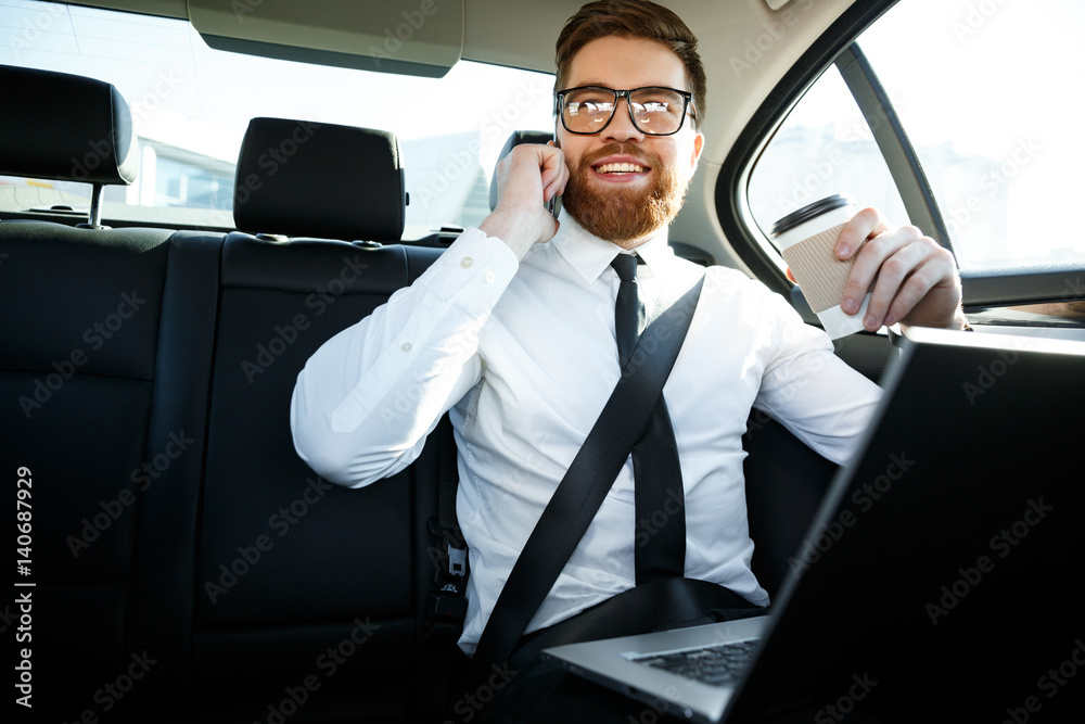 Smiling business man with laptop talking on phone
