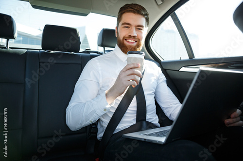 Smiling business man with laptop holding cup of coffee © Drobot Dean