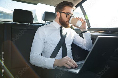 Bearded business man using laptop and drinking coffee © Drobot Dean