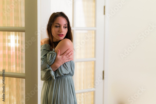 Middle aged caucasian woman in medieval dress and choker poses with a glass door