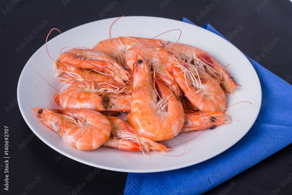 king prawns in a white plate on a black background king prawns in a white plate on a black background