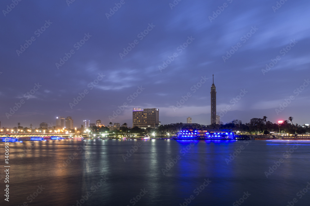 Cairo city center at twilight, the Kasr El Nile Bridge and the island of Zamalek with its colorful boats on the Nile river.