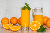 orange juice in glasses at light wooden background