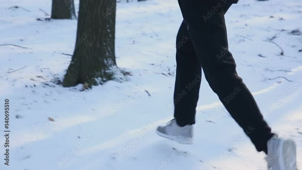 Athlete running outdoors in cold winter weather. Snow. Slow motion Athlete running outdoors in cold winter weather. Snow. Slow motion