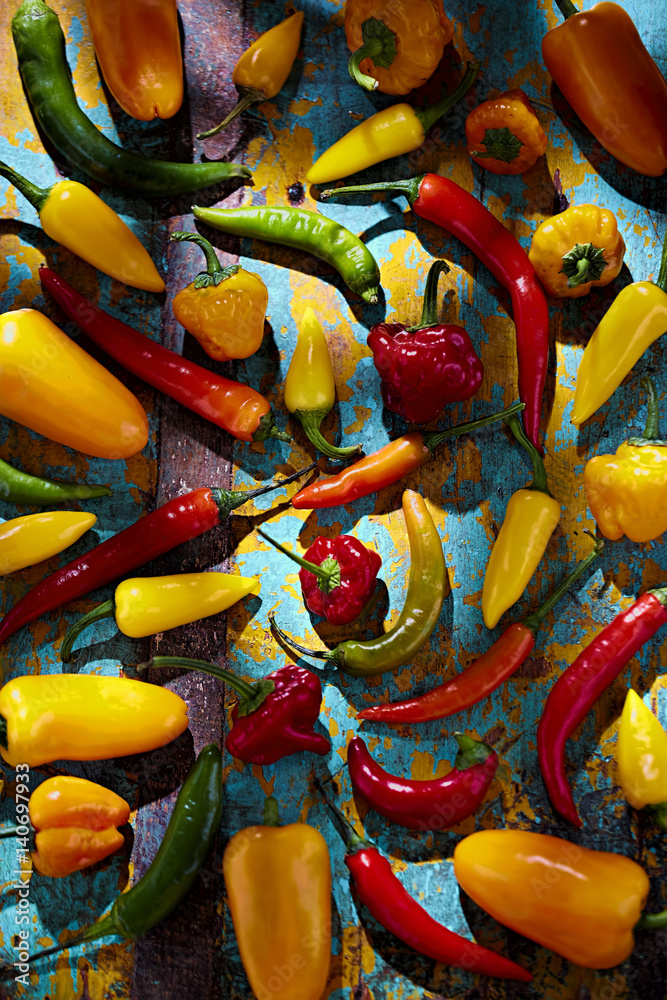 Green, red, yellow and orange peppers on blue background