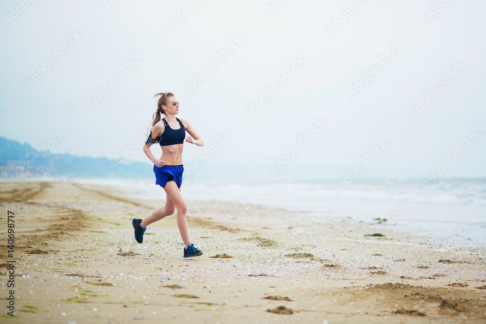 Young fitness running woman jogging on beach Young fitness running woman jogging on beach