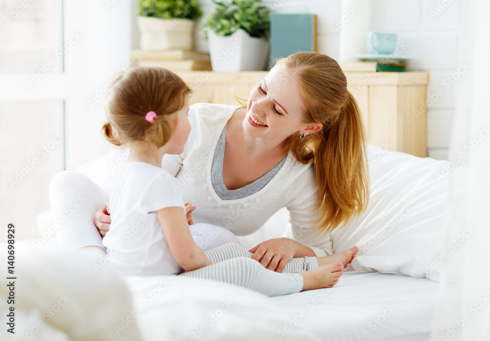 Fototapeta premium Happy family mother and baby daughter playing in bed