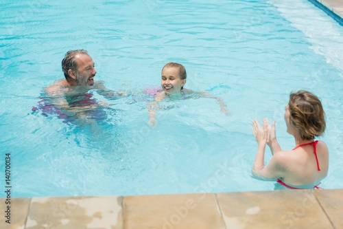 Happy parents and daughter having fun in pool