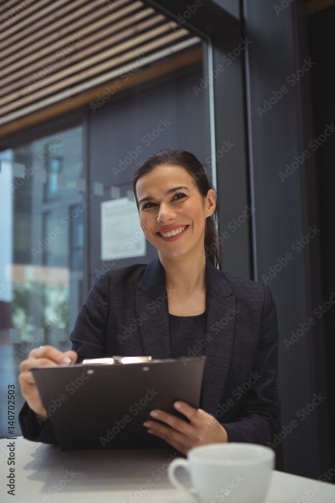 Happy businesswoman writing on clipboard Happy businesswoman writing on clipboard