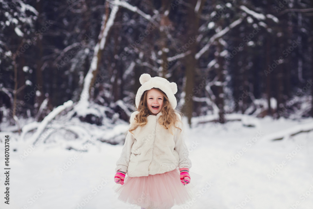 winter portrait of adorable smiling kid girl in hat