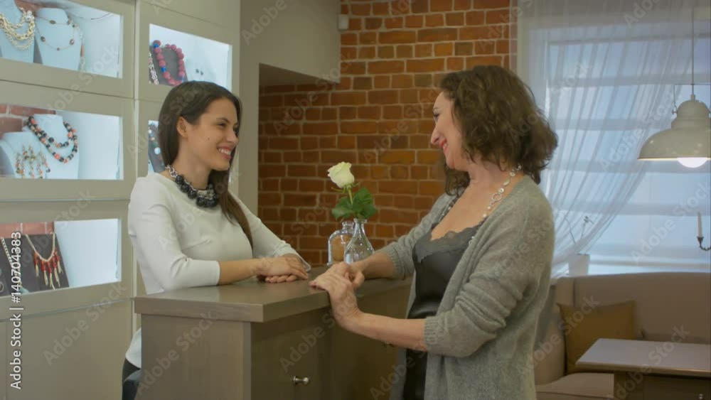 Attractive woman comes to jewelry store and talking to young seller consultant about buying something