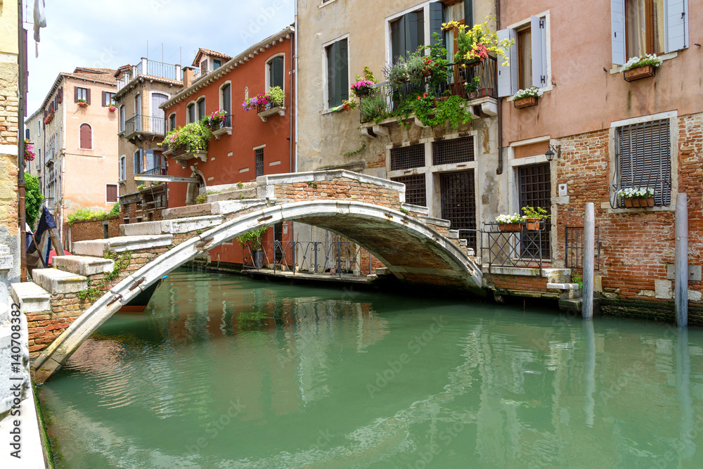 Venetian stone bridge. View of one of the typical canals and houses of the famous city of Venice.