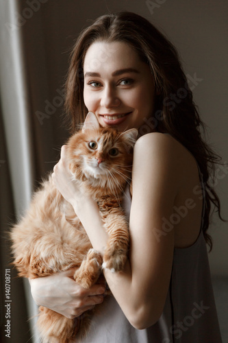 Vertical image of smiling woman in nightie with cat