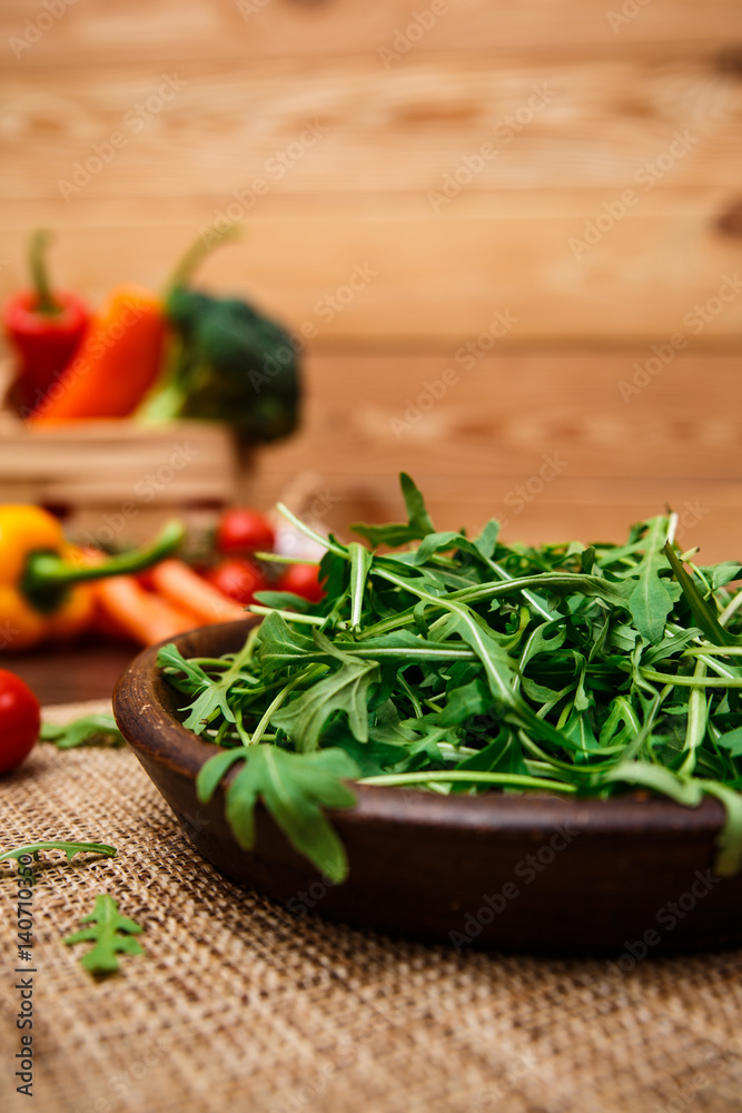 Arugula leaves in bowl. Fresh salad. Natural raw vegetables. Organic bio food on rustic wooden table. Arugula leaves in bowl. Fresh salad. Natural raw vegetables. Organic bio food on rustic wooden table.