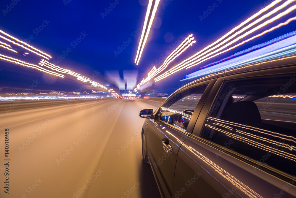 Fototapeta premium View from Side of Car moving in a night city, Blured road with lights with car on high speed. Concept rapid rhythm of a modern city.