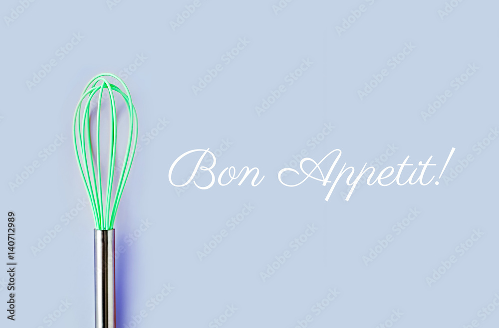 Neon green culinary whisk top view on colorful background. Bon Appetit text. Cook food concept Neon green culinary whisk top view on colorful background. Bon Appetit text. Cook food concept