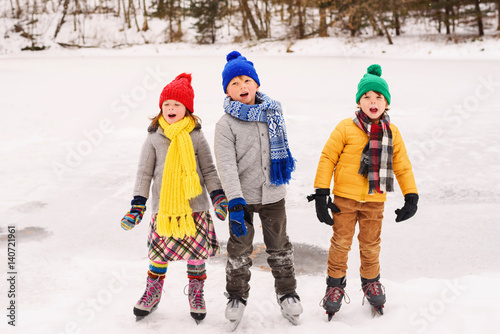 Three children on ice skates singing carols photo